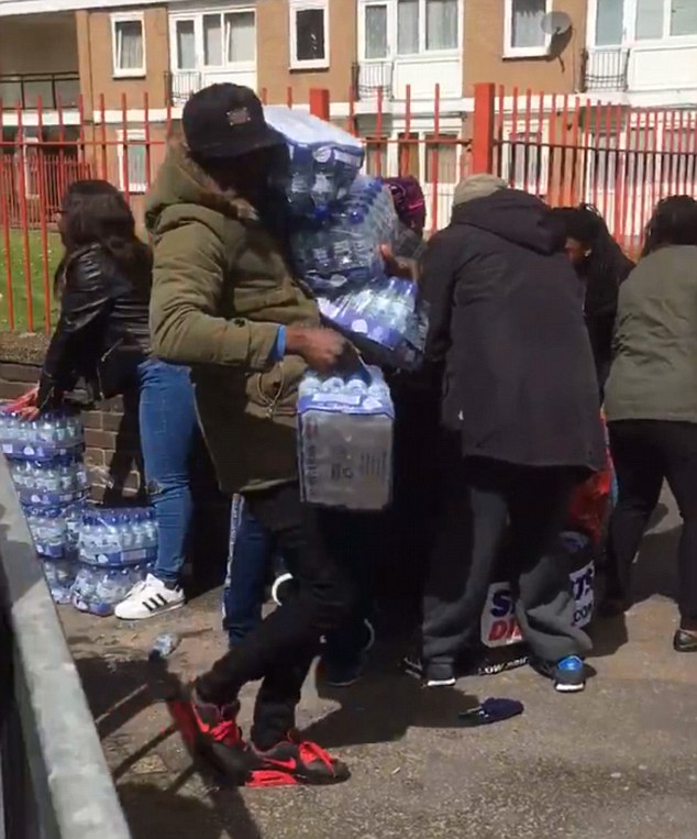 This is the shocking moment people armed with shopping trolleys stole trays of bottled water intended for London Marathon runners. Dozens of people swarmed around water stations at the side of the 26.2-mile route in Deptford, South East London, as they shamelessly began loading litres of Buxton water into their bags.