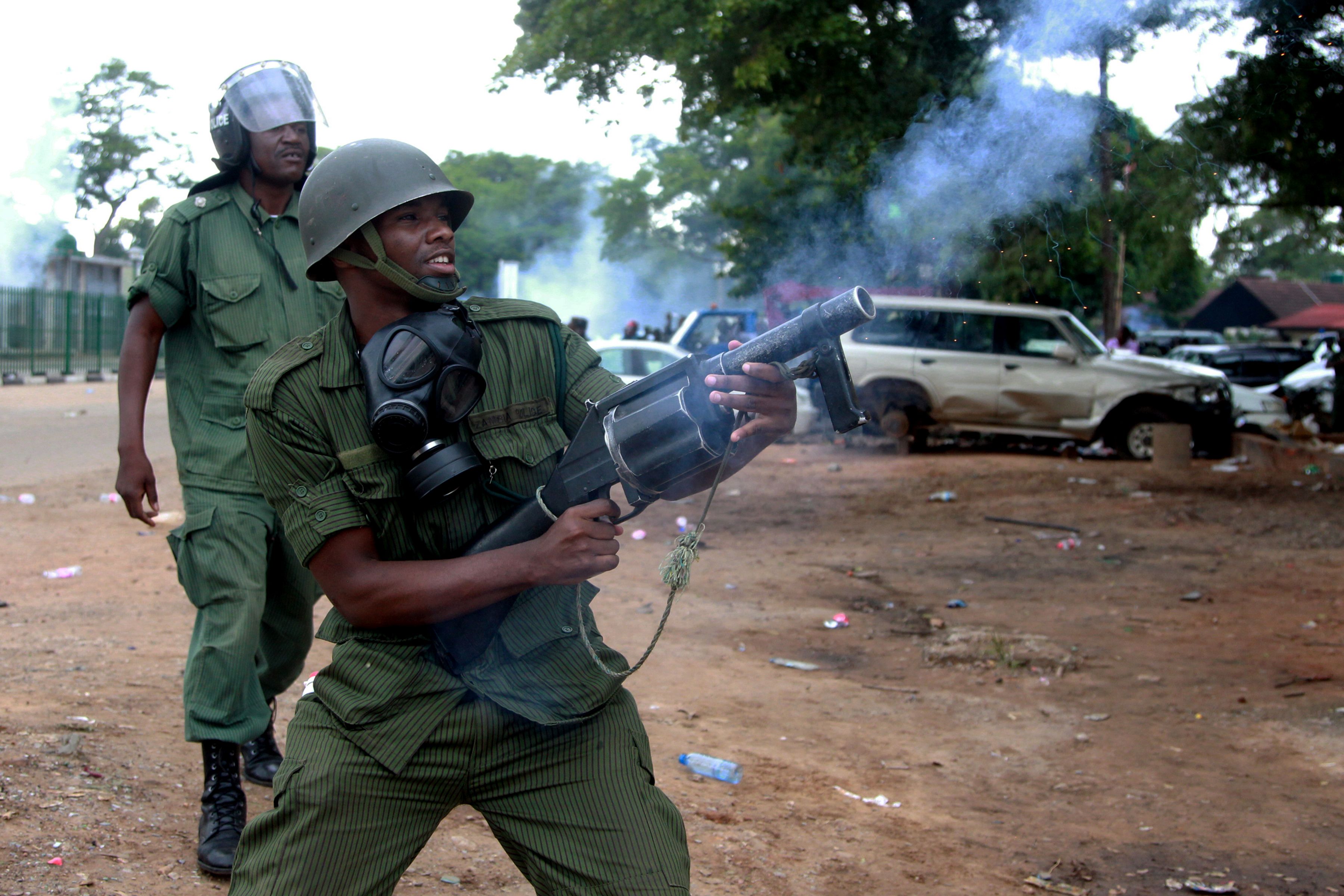A Zambian police officer fires tear gas to supporters of the opposition United Party for National Development (UPND) outside the Woodlands Police Station in Lusaka on March 2, 2016. The supporters turned to show solidarity to their party vice-president Geofrey Mwamba who has since been arrested and charged with unlawful drilling. / AFP / Dawood SALIM        (Photo credit should read DAWOOD SALIM/AFP/Getty Images)